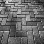 Monochrome image of brick pavement in herringbone pattern creating texture.